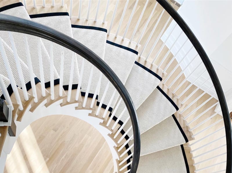 Curved staircase with black and white rug